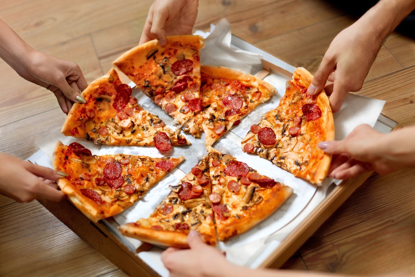 people grabbing slices of pizza